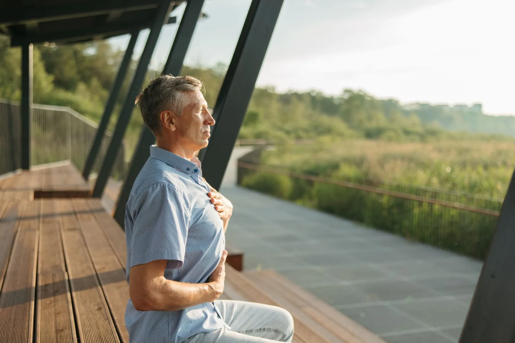 An older man taking a slow breath outdoors