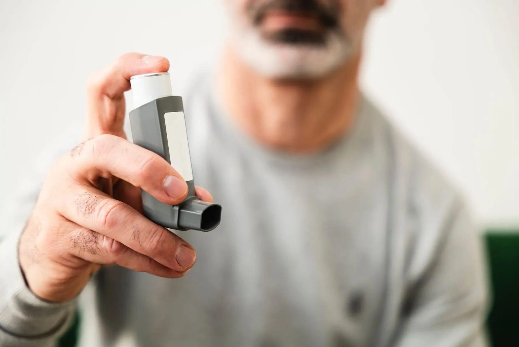 A man holding a reliever inhaler